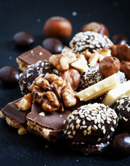 Chocolates, sweets, hazelnuts and walnuts on a dark background,