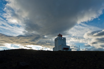 Lighthouse at Dyrholaey rock at sunset with dramatic sky