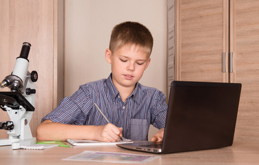 Schoolboy doing his school homework project writing notes.