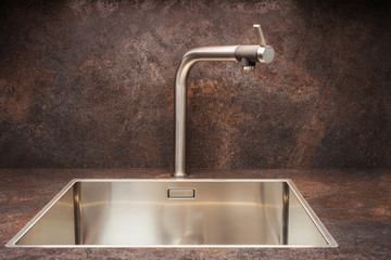 Modern designer chrome water tap over stainless steel kitchen sink.