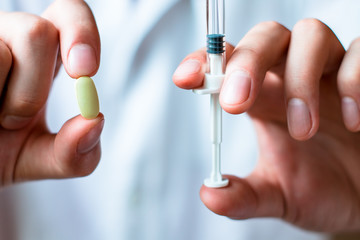 Syringe, pills or capsules, medical injection in hand, palm