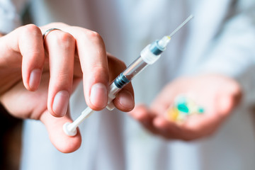 Syringe, pills or capsules, medical injection in hand, palm