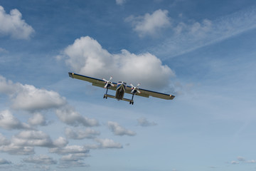 Zweimotoriges Propellerflugzeug im Landeanflug vor blauem Wolkenhimmel
