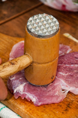 Hammering steak meat on the wooden board