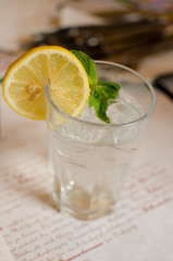 The glass with lemonade, lemon, mint and ice cubes