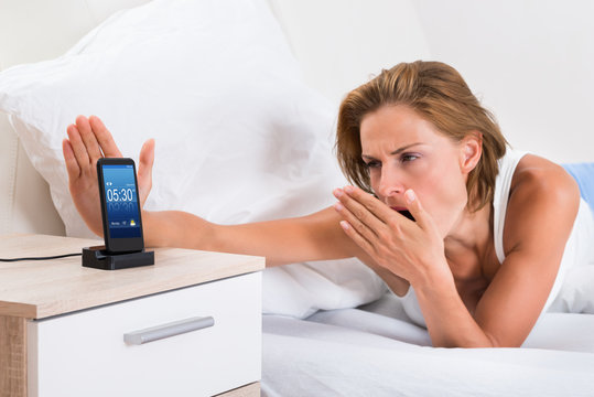 Woman Yawning While Snoozing Alarm