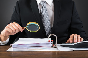 Businessman Inspecting Invoice With Magnifying Glass