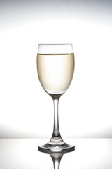 White wine pouring into wineglass on white background