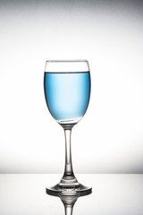 Blue cocktail in wine glass on white background