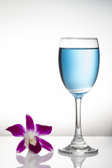Blue cocktail in wine glass and orchid flower on white backgroun