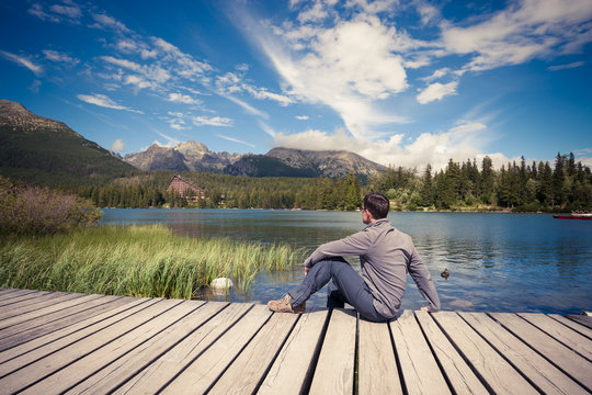 Man sitting near alpine mountain lake
