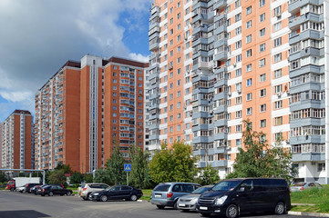 Fototapeta na wymiar Жилые многоэтажные дома на улице и припаркованные на улице автомобили 