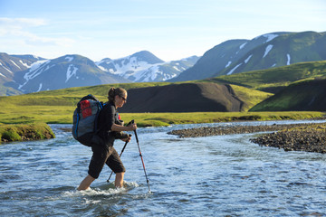 Female hiker crossing a river on the Laugavegur trail on Iceland.