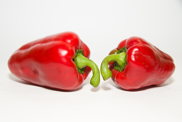 Two ripe red peppers on over white