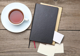 Blank business cards with pen, notebook and tea cup on wooden