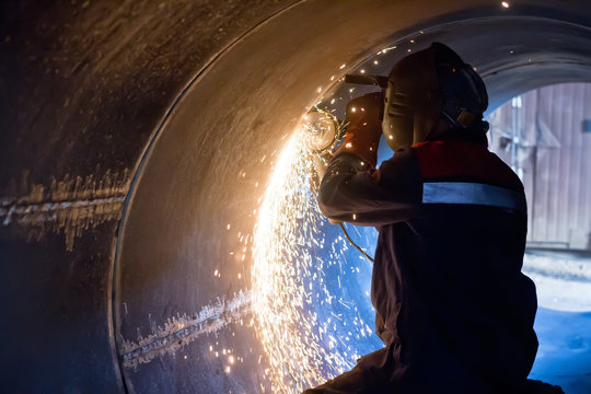 welder carries out mechanical cleaning of root surfaces of weld