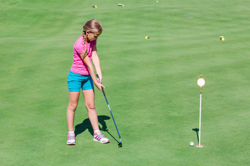 Cute little girl playing golf on a field