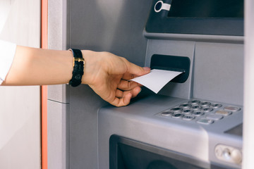 Female hand holding a receipt obtained from the ATM after withdr
