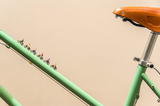 Miniature people biking on vintage bike.