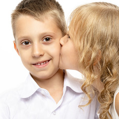 Little beautiful girl kisses a happy boy.