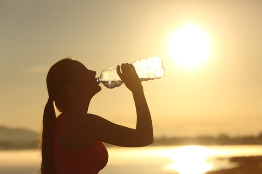 Fitness woman silhouette drinking water from a bottle