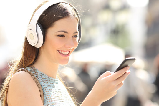 Woman listening music from a smart phone in the street