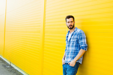 young handsome man with headphones on yellow wall