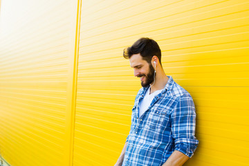young handsome man with headphones on yellow wall