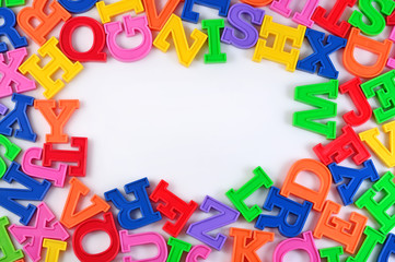 Fototapeta premium Frame of plastic colorful alphabet letters on a white