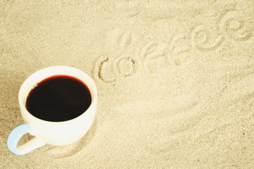 Cup of coffee put in sand at the beach, Relax concept.
