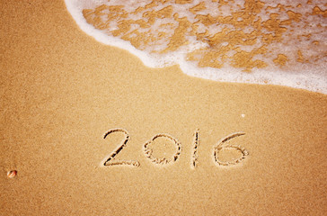 new year 2016 written in sandy beach. image is retro filtered
