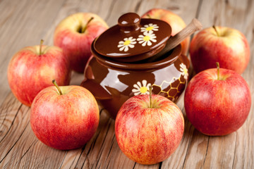 Ripe red apples and honey pot on wooden table