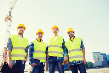 group of smiling builders with tablet pc outdoors