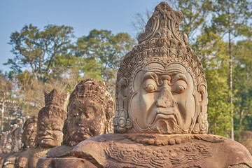 Fototapeta na wymiar Statues of ancient khmer warrior heads carry giant snake decorating bridge to Bayon at Angkor Wat complex, Siem Reap, Cambodia.