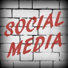 The phrase Social Media in red text on a brick wall background processed in black and white for effect