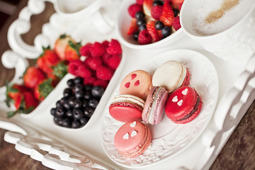 Sweet breakfast with strawberry, blueberry, raspberry, cappuccino and muesli on white vintage tray