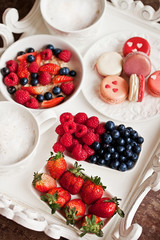 Sweet breakfast with strawberry, blueberry, raspberry, cappuccino and muesli on white vintage tray
