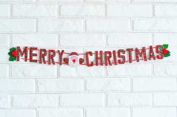 Merry Christmas sign hanging on white brick wall as decoration