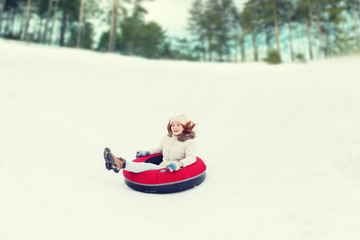 happy teenage girl sliding down on snow tube