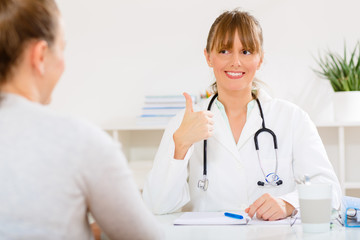 Young woman at her doctors receiving good news about her health