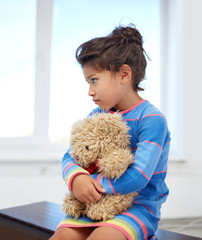 sad little girl with teddy bear toy at home