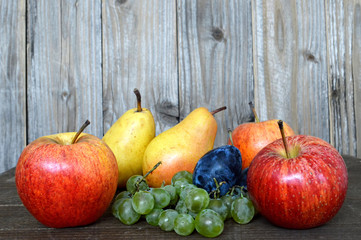 Mixed autumn fruits on wooden background
