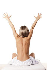 Obraz premium rear view of a young and happy naked woman sitting on a bed