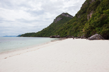 Beach on tropical island. Clear blue water, sand, clouds. 