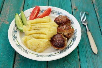 Mashed potatoes and three homemade meat chops with fresh cucumbe