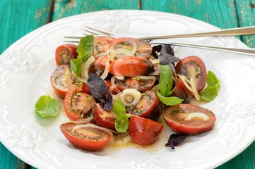 Salad with organic tomatoes and fresh basil leaves on old turquo