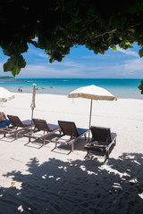 Beach on tropical island. Clear blue water, sand, clouds. 