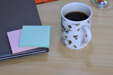 buongiorno in ufficio, tazza di caffe vicino ad un computer e dei notes colorati