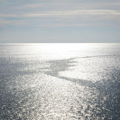 Calm sea with a boat trail. Sunlight on the water surface. Aged photo. Tranquil seascape. Autumn mediterranean sea near Gaeta, Latina province, Italy.