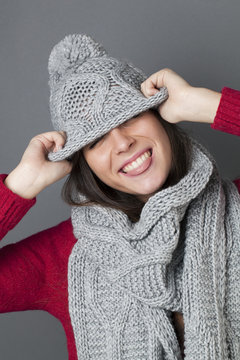 happy female teenager joking in hiding herself under winter hat